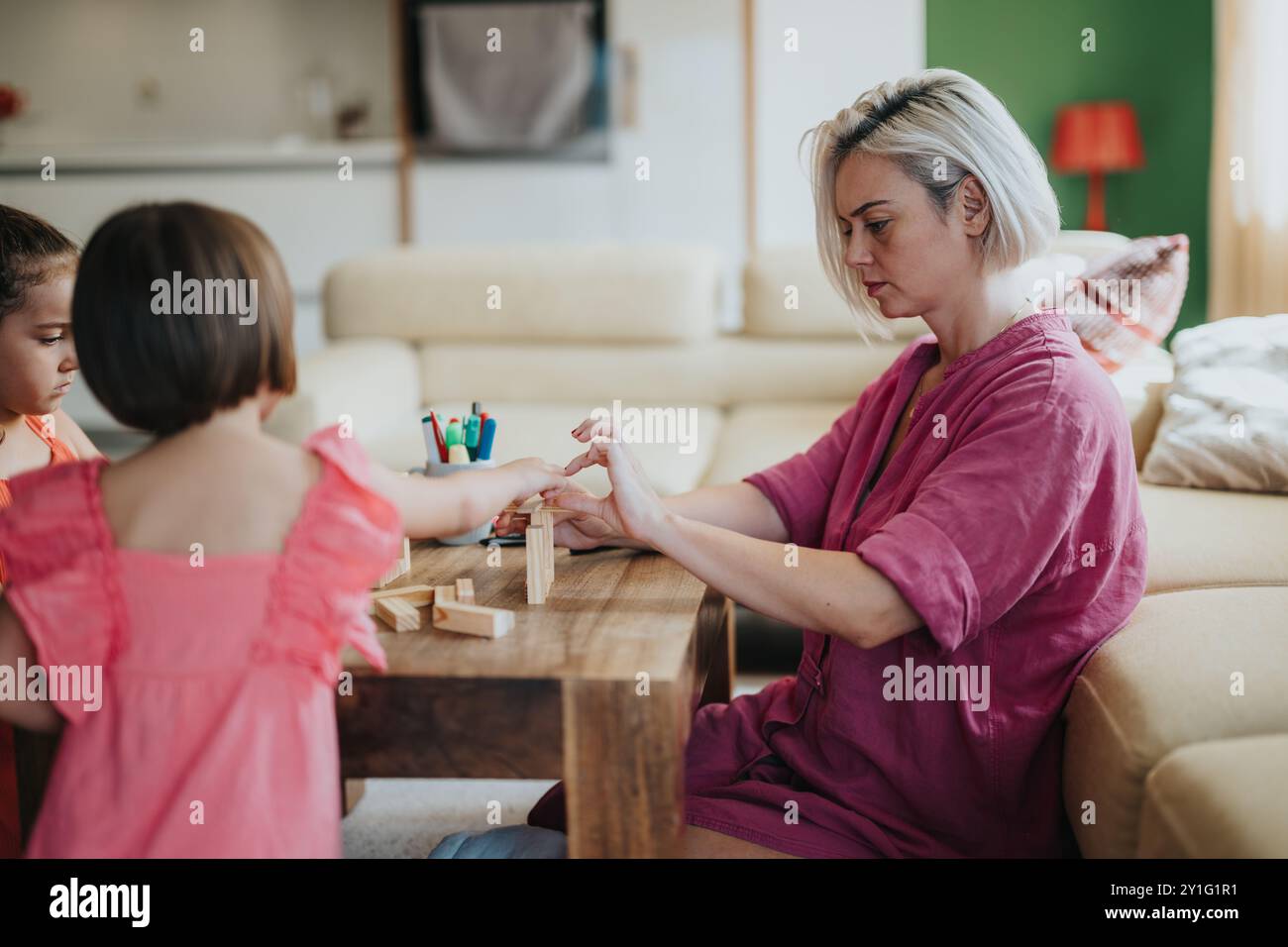 Mother and children playing with wooden blocks at home Stock Photo - Alamy