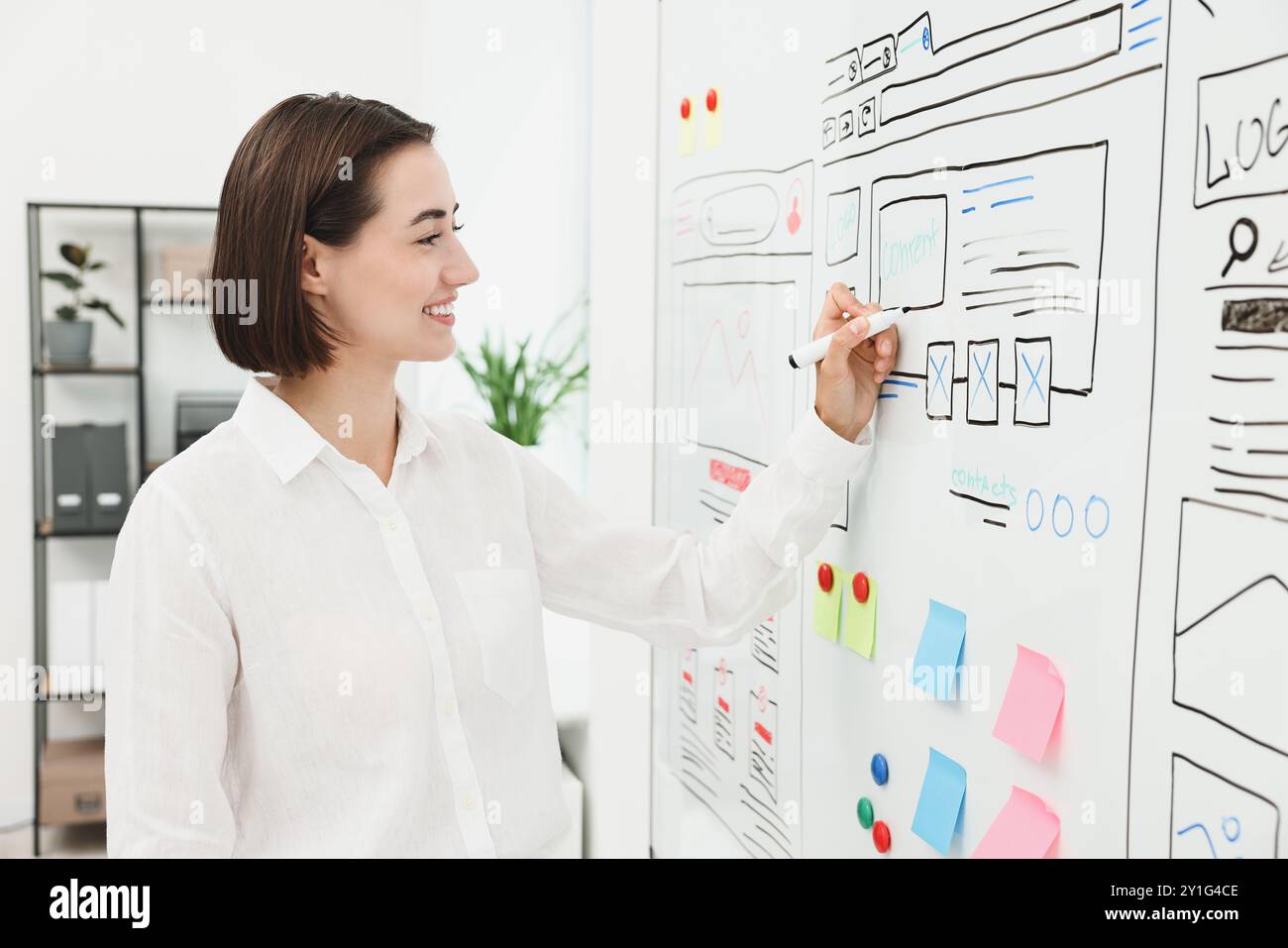 Developing UI design. Woman drawing website wireframe on whiteboard indoors Stock Photo