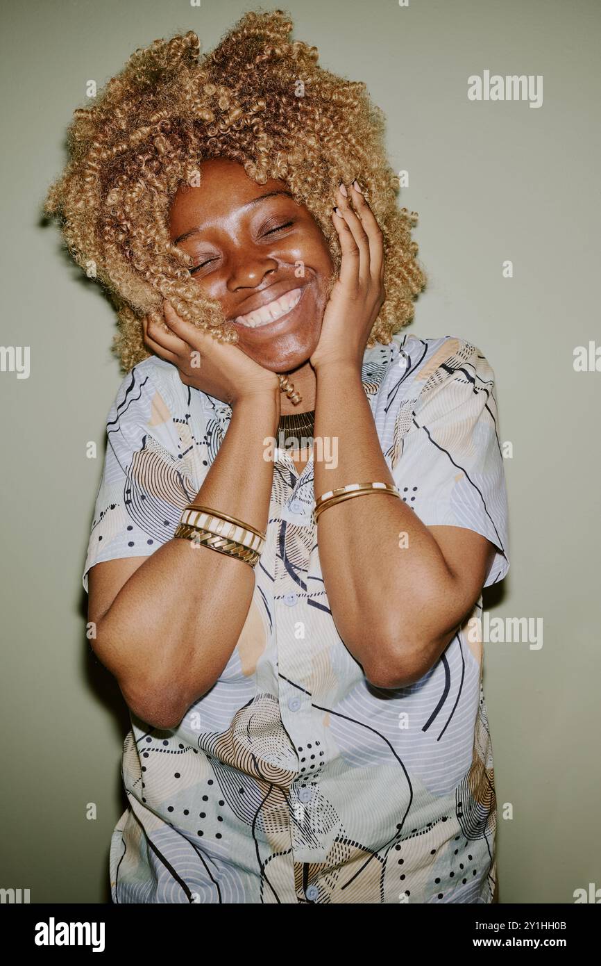 Vertical portrait of young blonde curly haired woman smiling widely Stock Photo