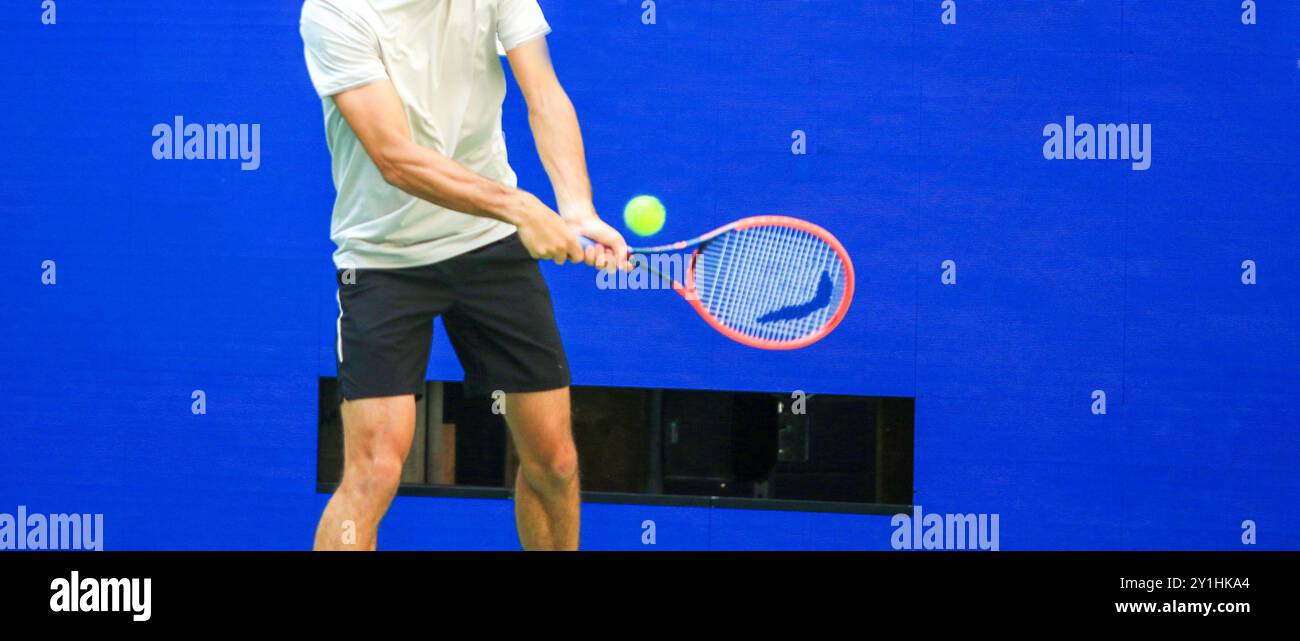 One man swinging at a tennis ball using two hands on his racket during ...