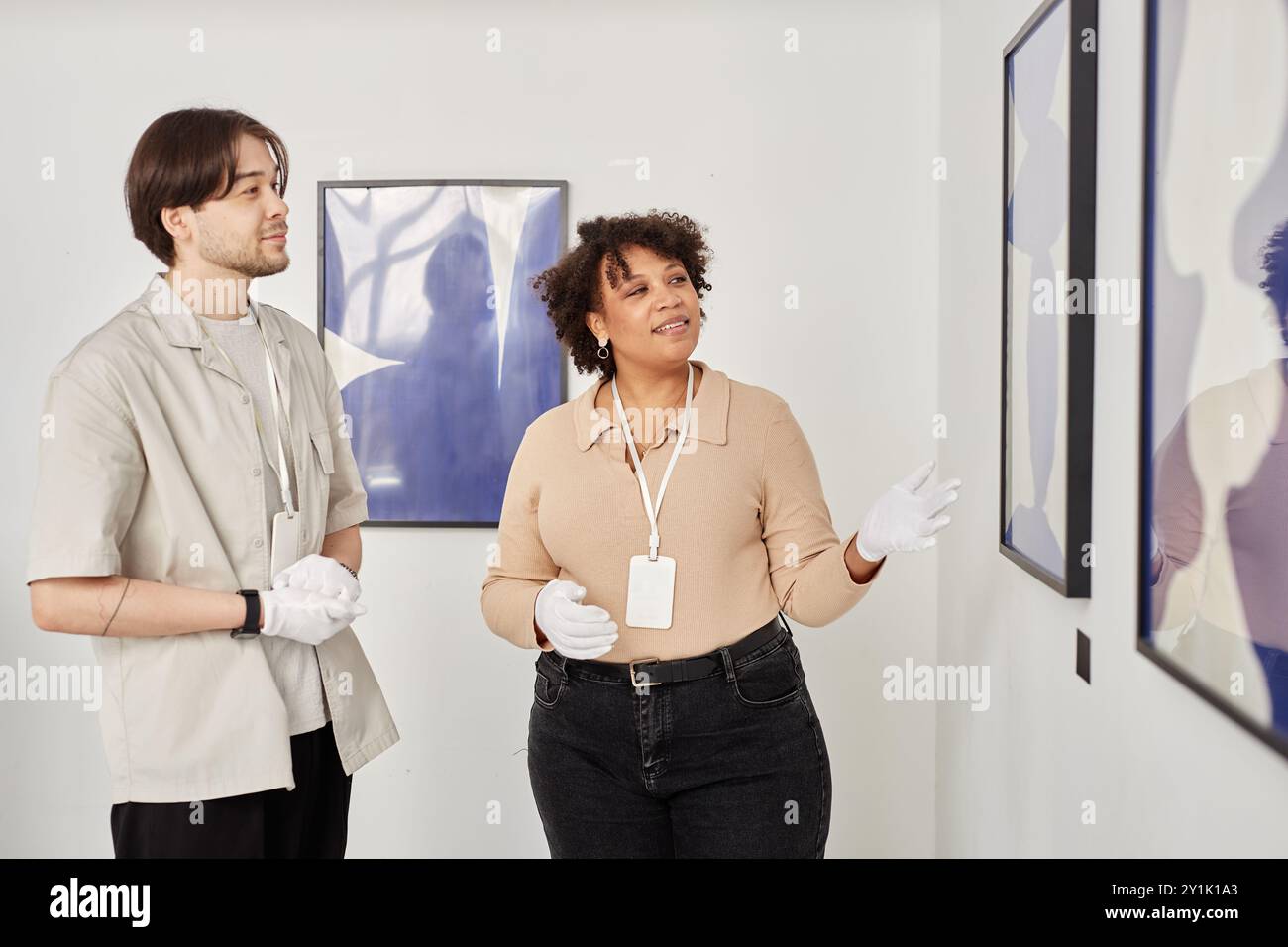 Portrait of Black woman as art curator pointing at paintings while ...