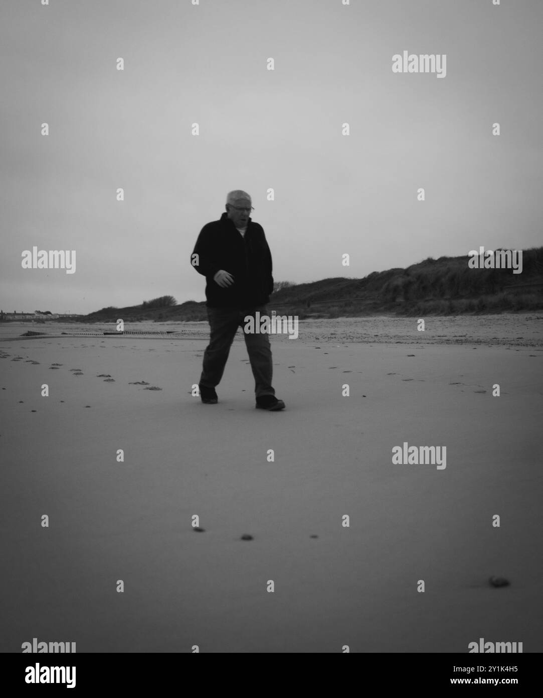 man walking alone leaving footsteps across a deserted beach Stock Photo