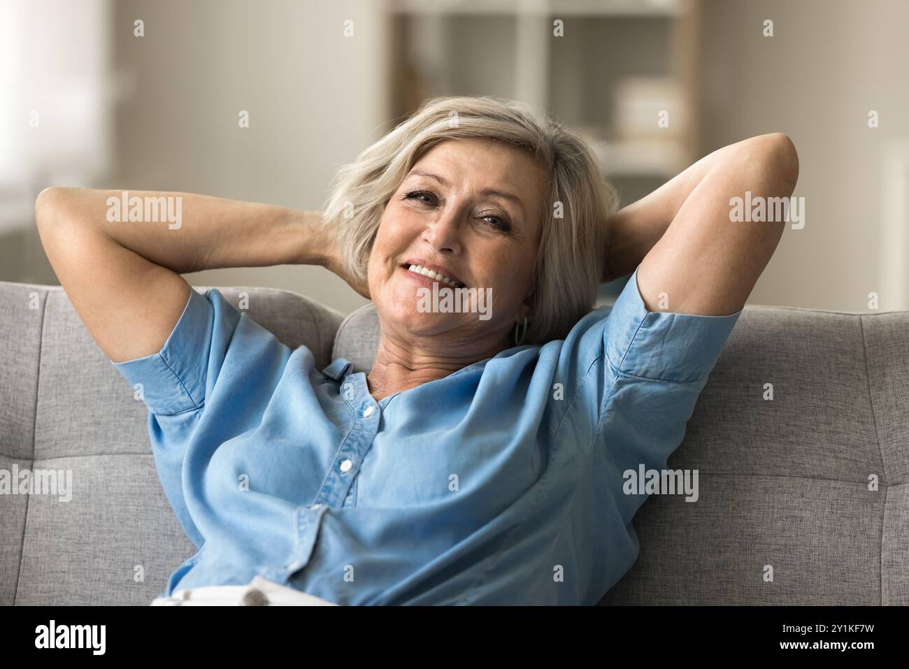Relaxed mature woman looking at camera lying leaned on sofa Stock Photo