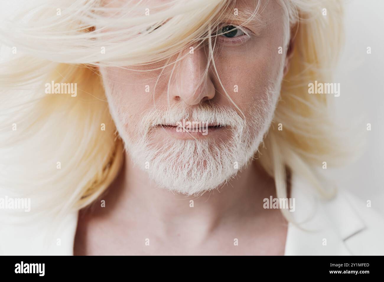 Portrait of a stylish man with long blonde hair and a beard against a ...