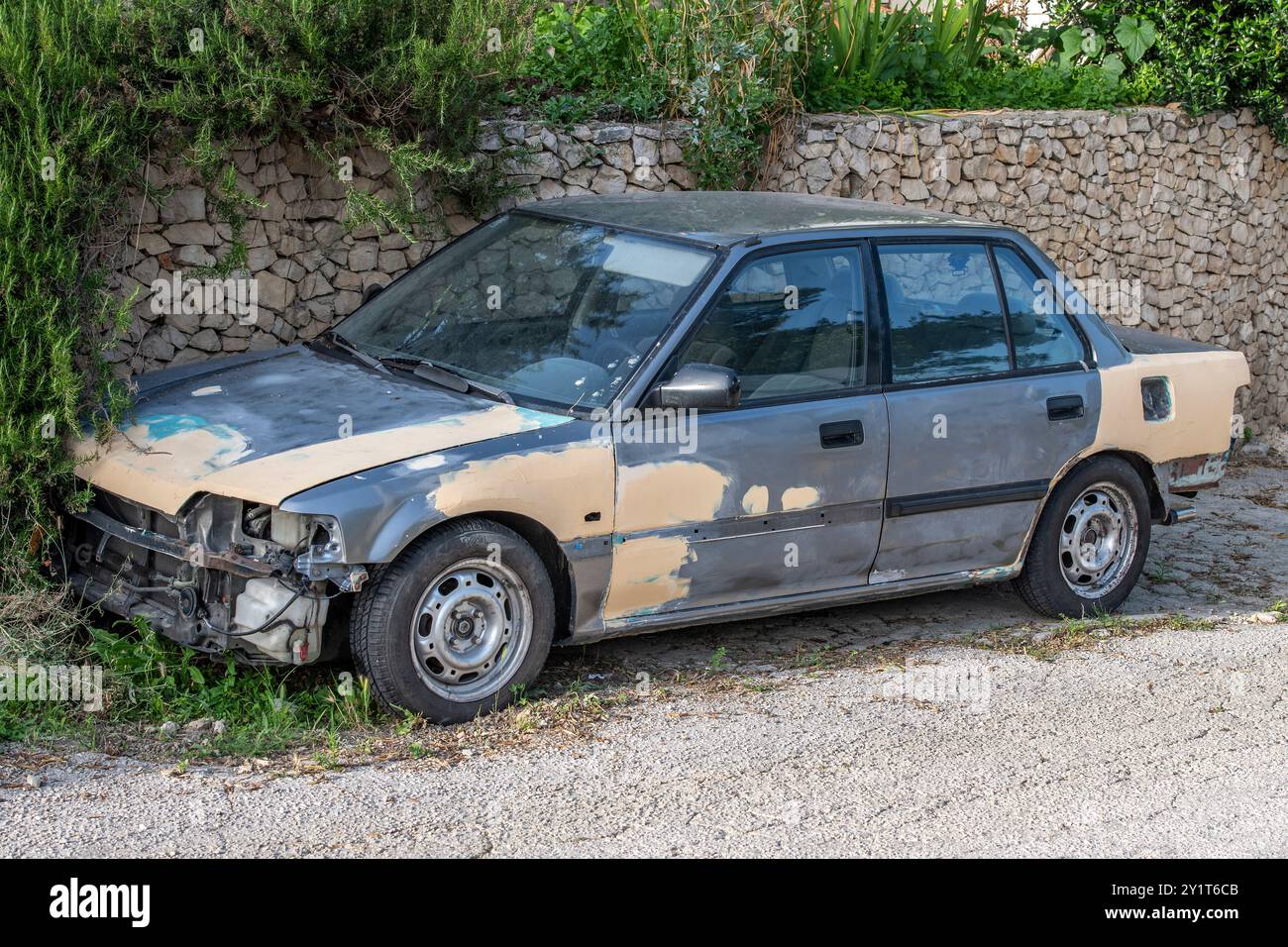 abandoned scrap car parked at the side of the road, motor left to rot and rust at the roadside Stock Photo