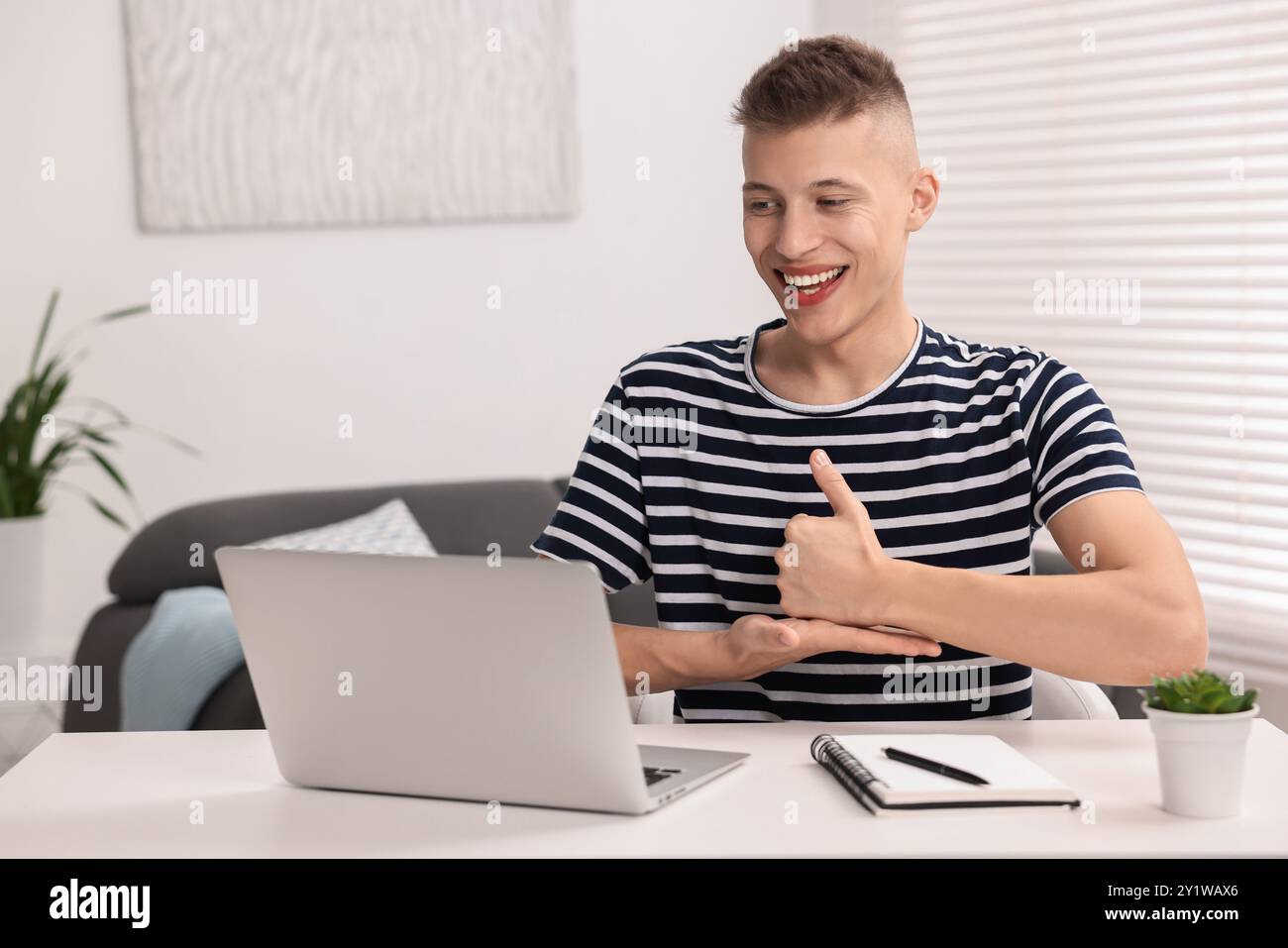 Young man using sign language during video call indoors Stock Photo