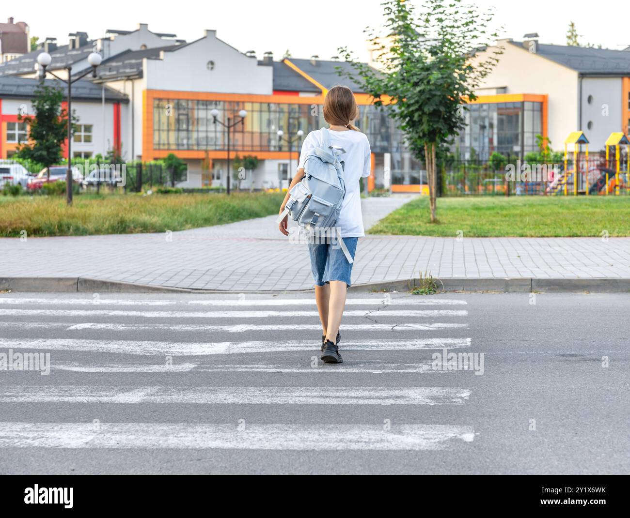 A schoolgirl crosses a pedestrian crossing. Background of the school ...