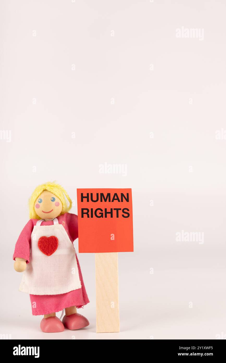 The image shows a wooden doll holding a red card with the words 