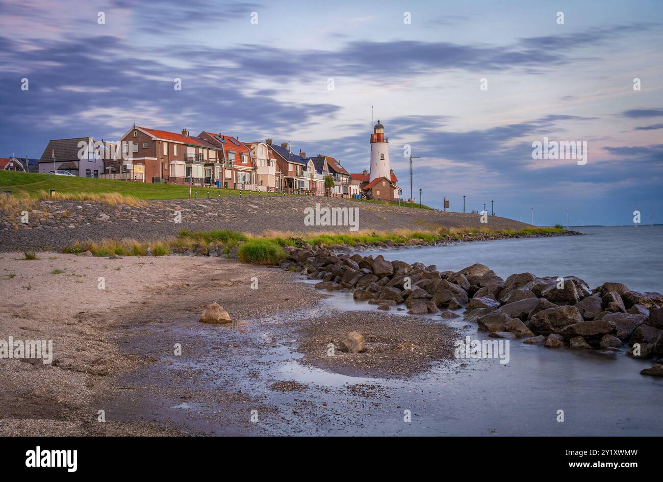 Townscape of Urk, Province Flevoland, The Netherlands. Waterfront with white lighthouse by sunset. Stock Photo