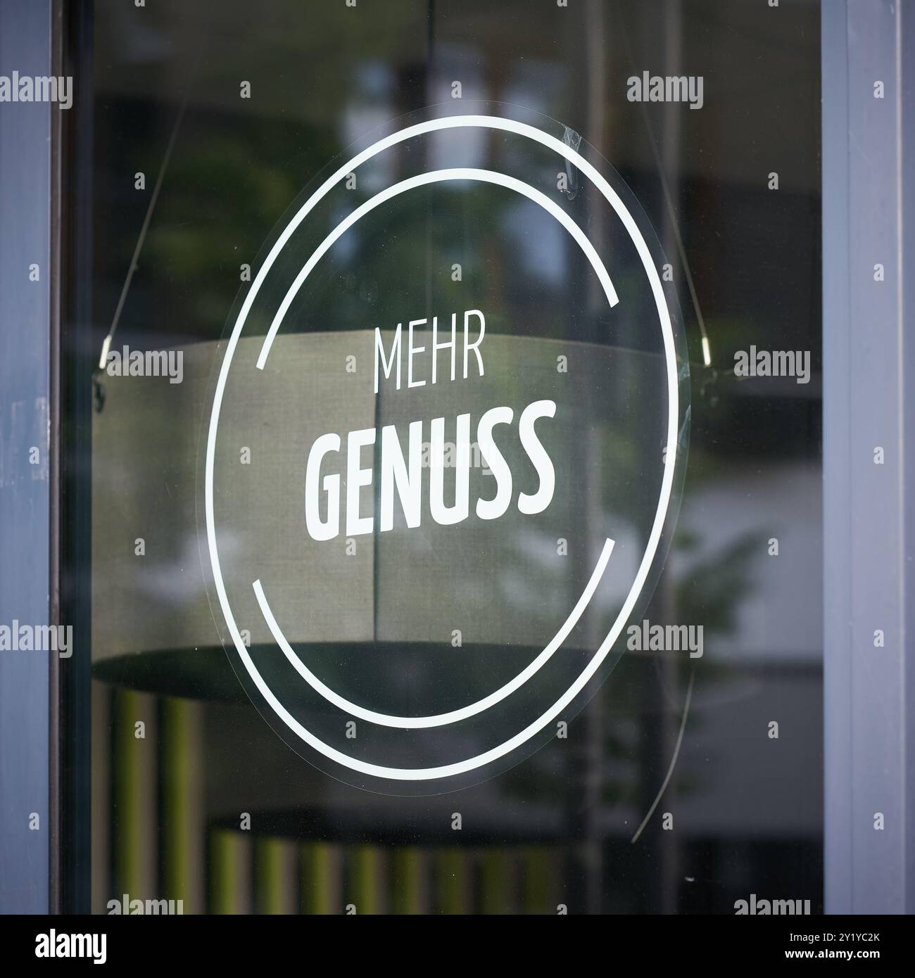 Sticker on the window of a store with the German inscription mehr Genuss. Translation: more pleasure Stock Photo