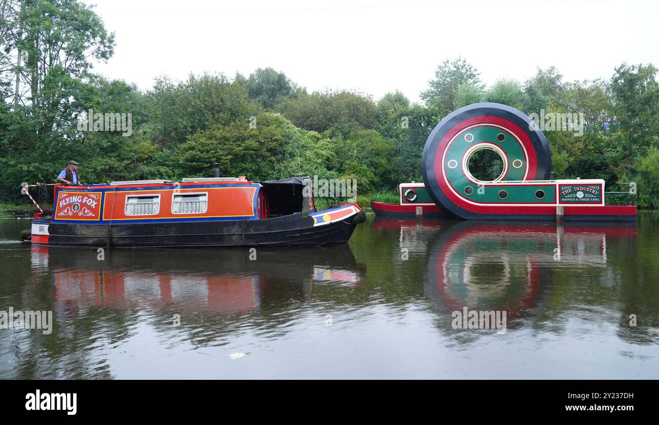 A canal boat passes the new sculpture of a canal boat after it was ...
