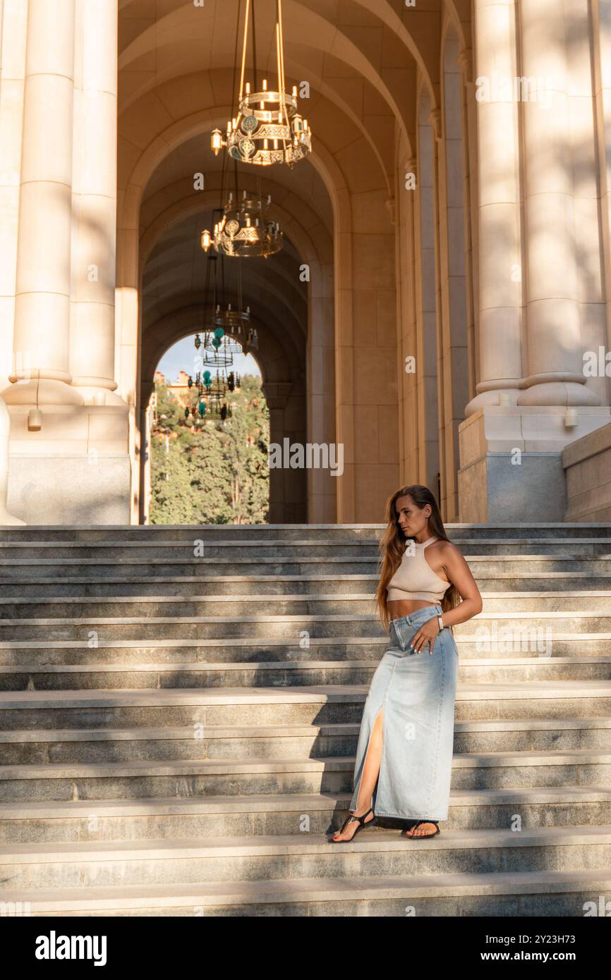 A woman in a long, light blue dress sits on the steps of a grand stone ...