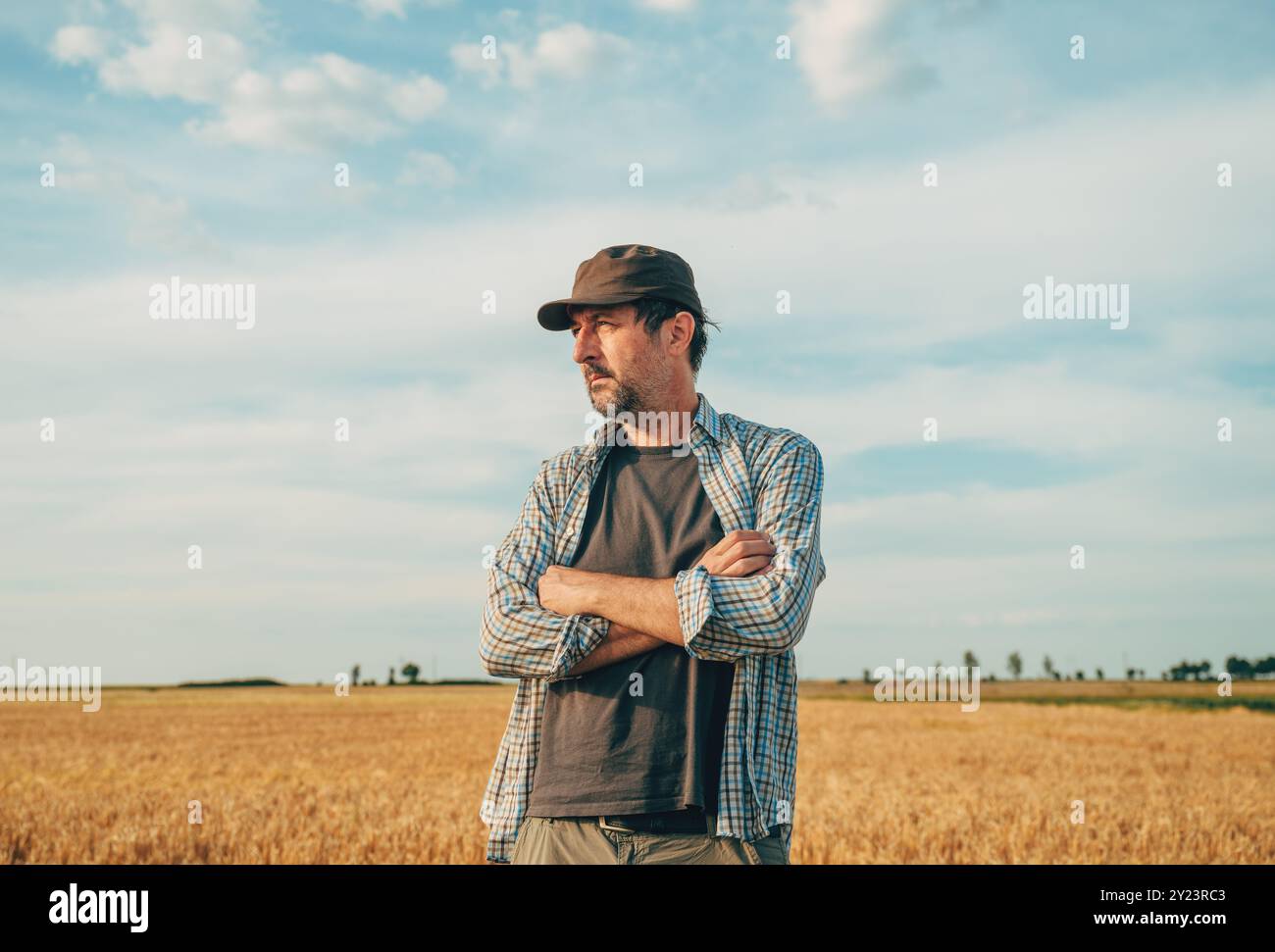Portrait of male farmer with trucker's hat standing in ripe wheat crop ...