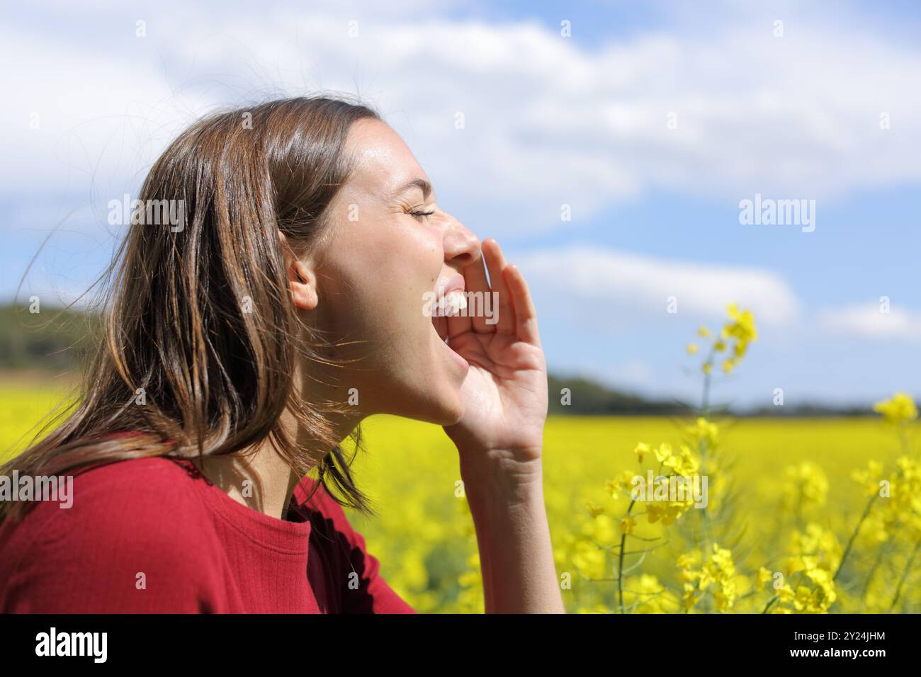 Side view portrait of a woman screaming in a flowers field Stock Photo