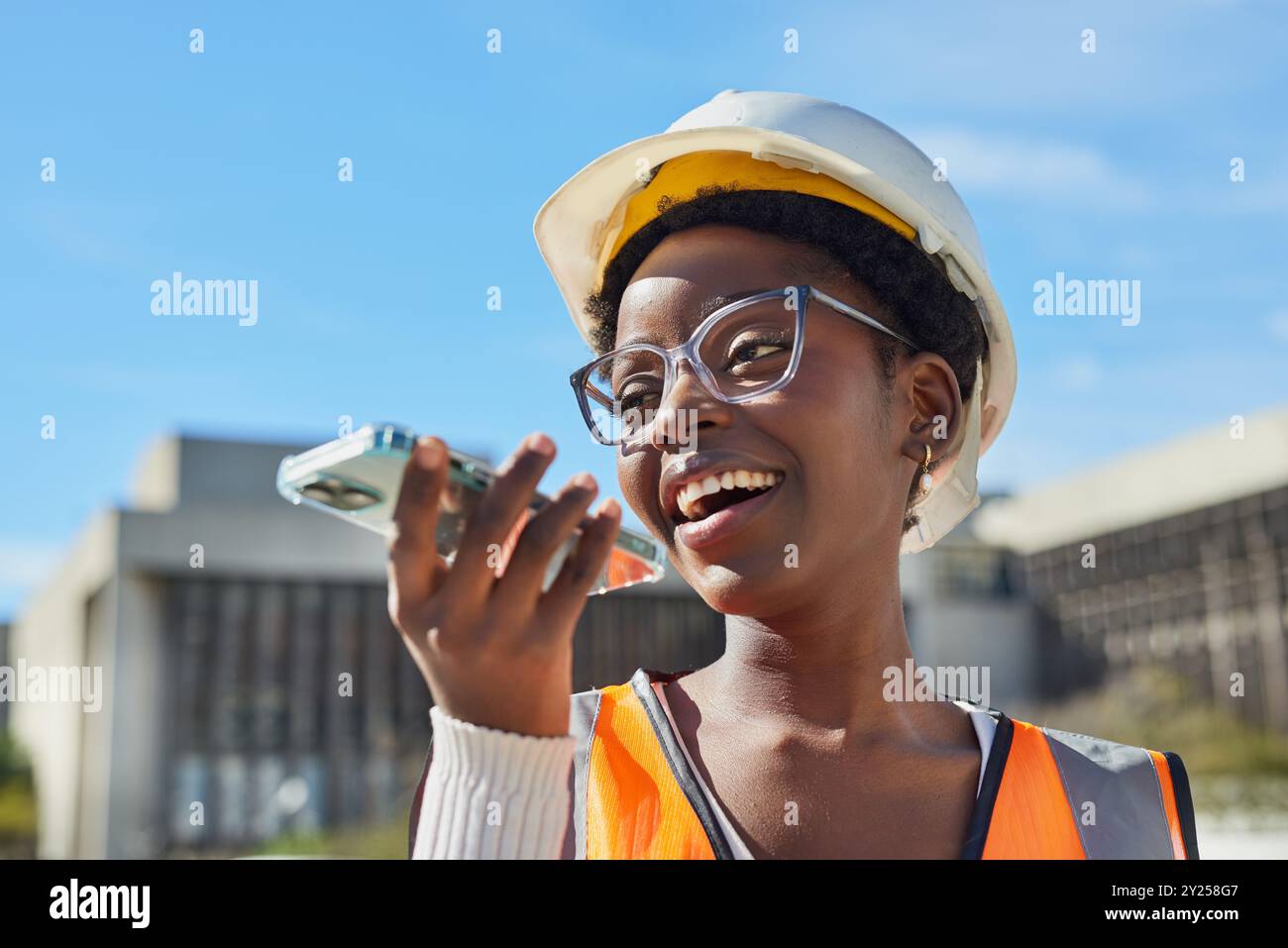Smiling Female Construction Worker Using Smartphone Outdoors Stock Photo
