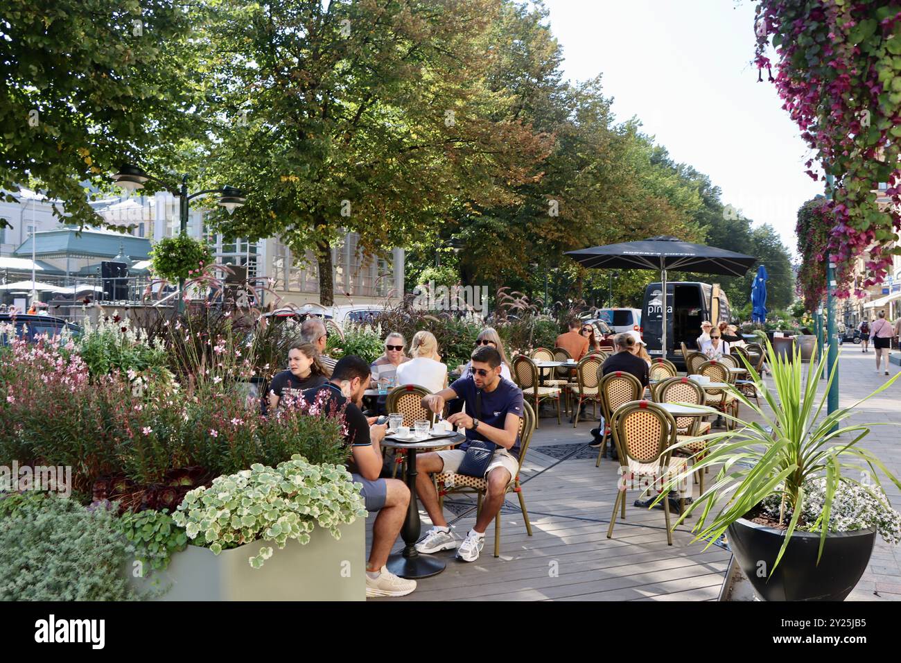 Sidewalk cafe amid extensive large pots of plantings of summer flowers and foliage on Pohjois Esplanadi street in central Helsinki, Finland Stock Photo