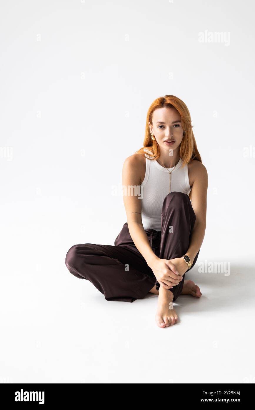young woman sitting on the floor n white background Stock Photo - Alamy