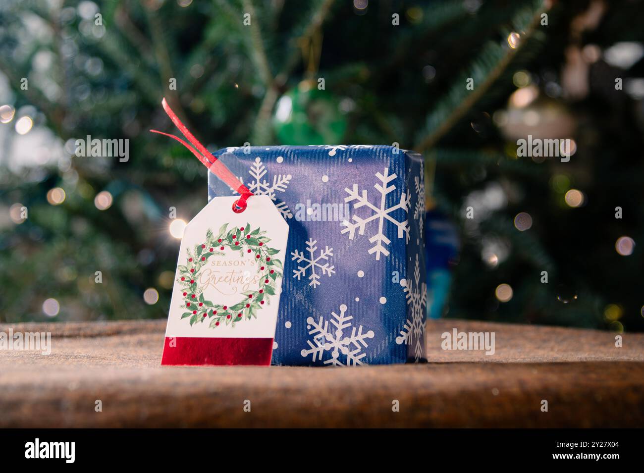 Square giftbox wrapped in snowflake paper with gift tag Stock Photo