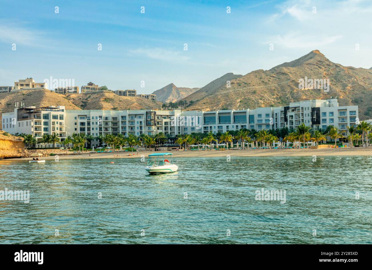 Qantab village white resort houses on the shore view from the sea bay with mountains in the background, Muscat, sultanate Oman Stock Photo