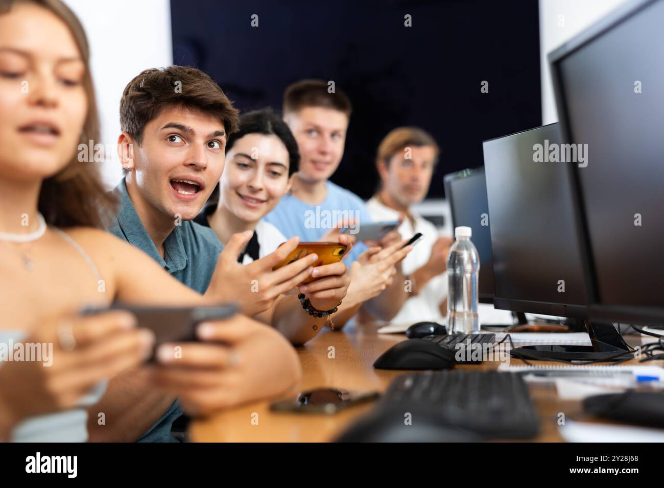 Excited young developer using mobile phone at IT startup presentation Stock Photo