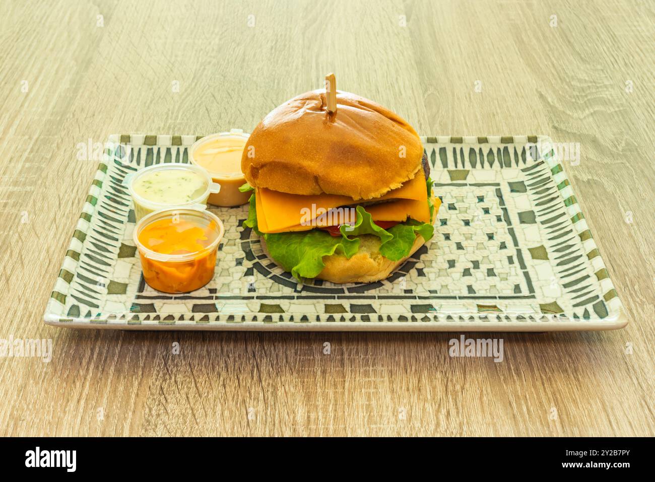 A burger with beef, vegetables, lots of cheese and sauces Stock Photo