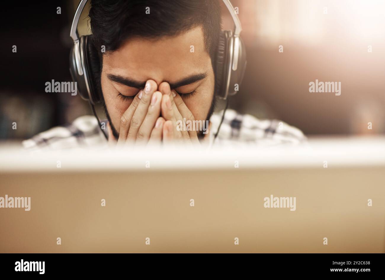 Headache Playing Computer Computer, headphones and Indian man in library with stress, headache ...