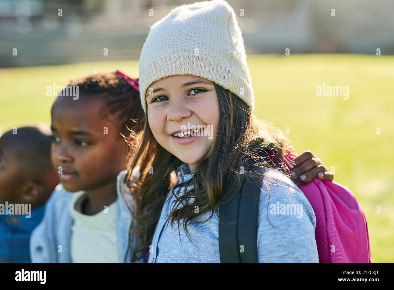Girl, child and portrait at school, grass and happy with friends, hug ...
