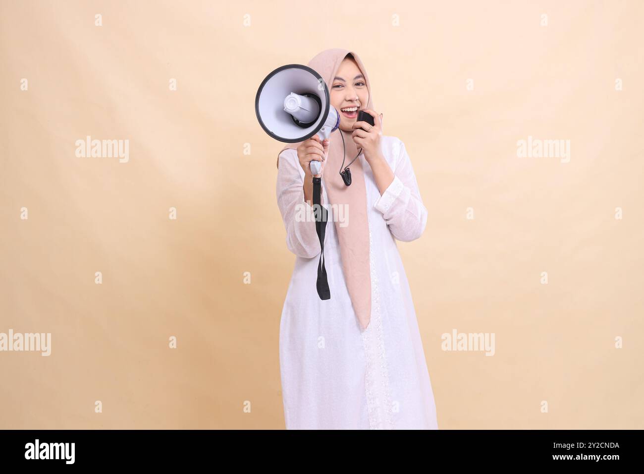 Asian Muslim woman wearing a hijab at the camera shouts with a cheerful ...