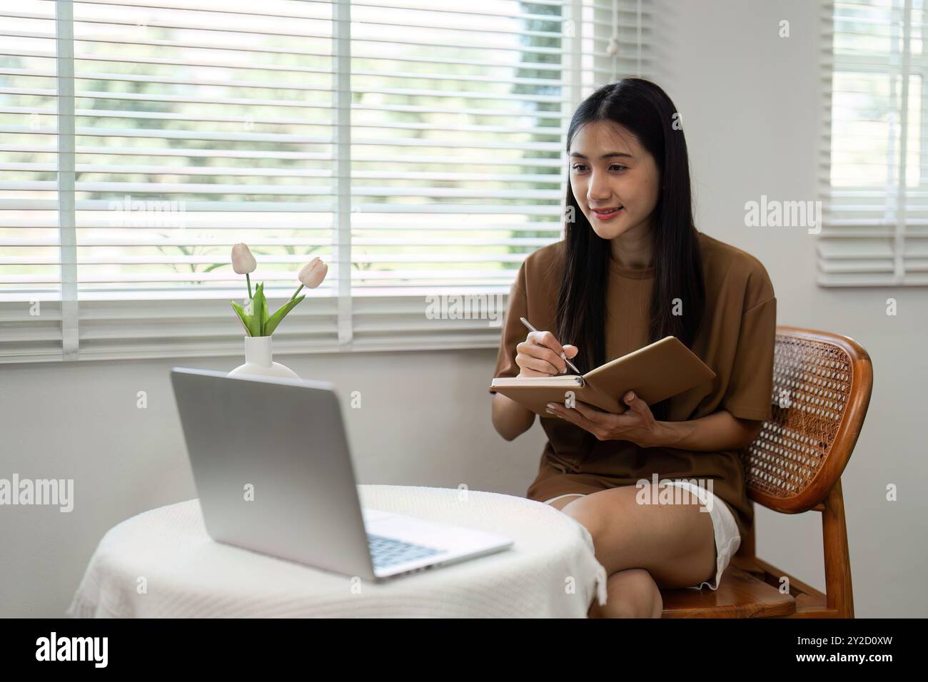 young-woman-working-from-home-with-laptop-and-notebook-in-bright-modern