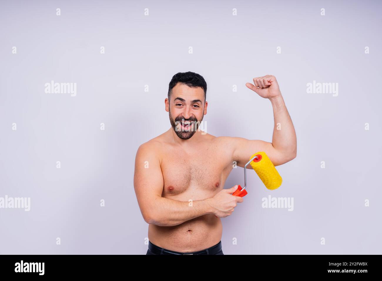 Young employee handyman using paint roller hold face isolated on background studio. Stock Photo