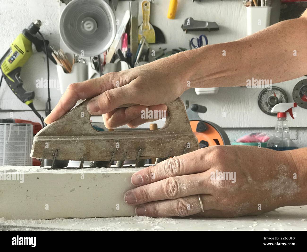 Hand holding a chemin de fer tool for stone carving with tools in the background Stock Photo