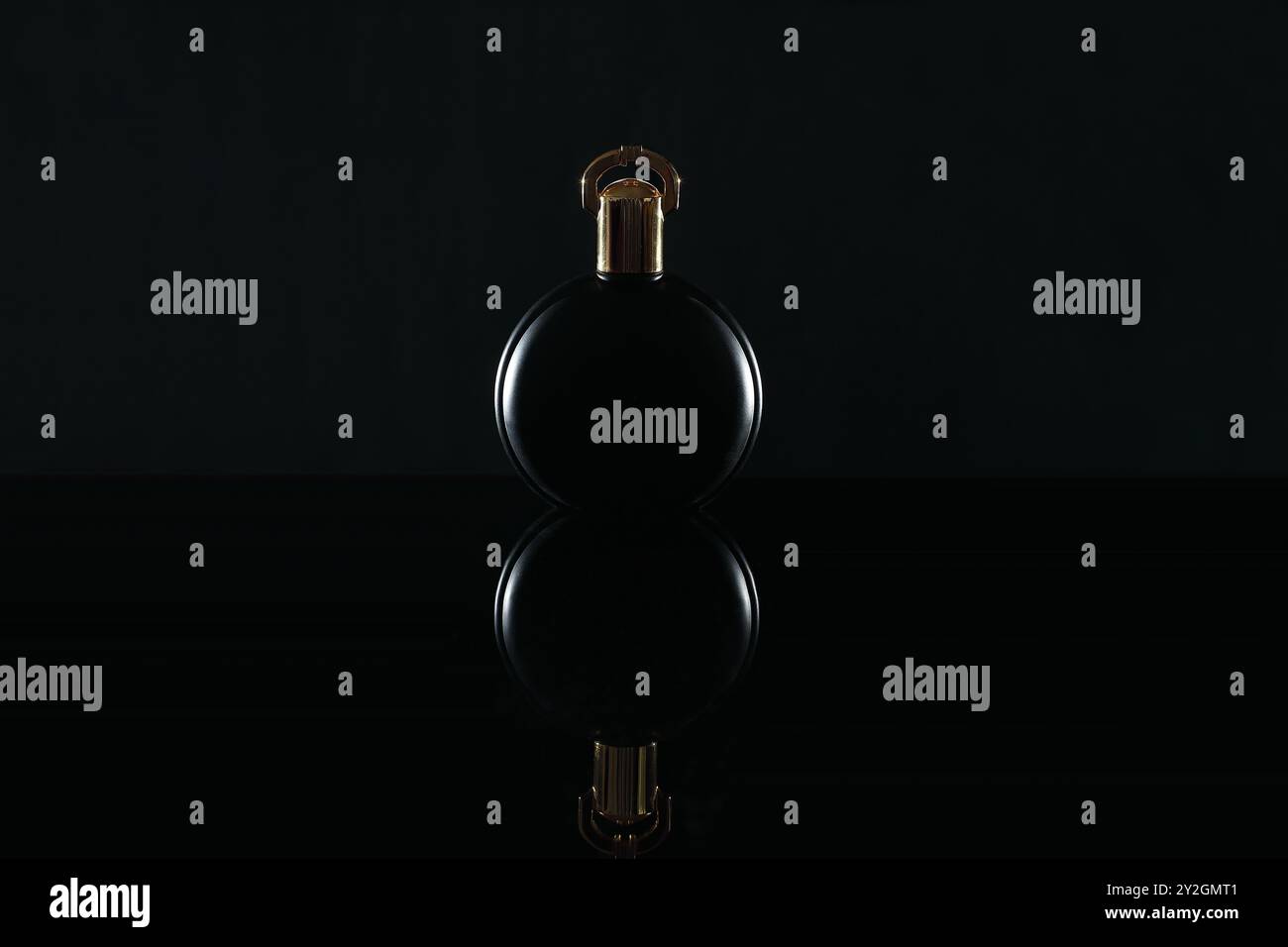 Perfume in black bottle with golden cap on a black background Stock Photo