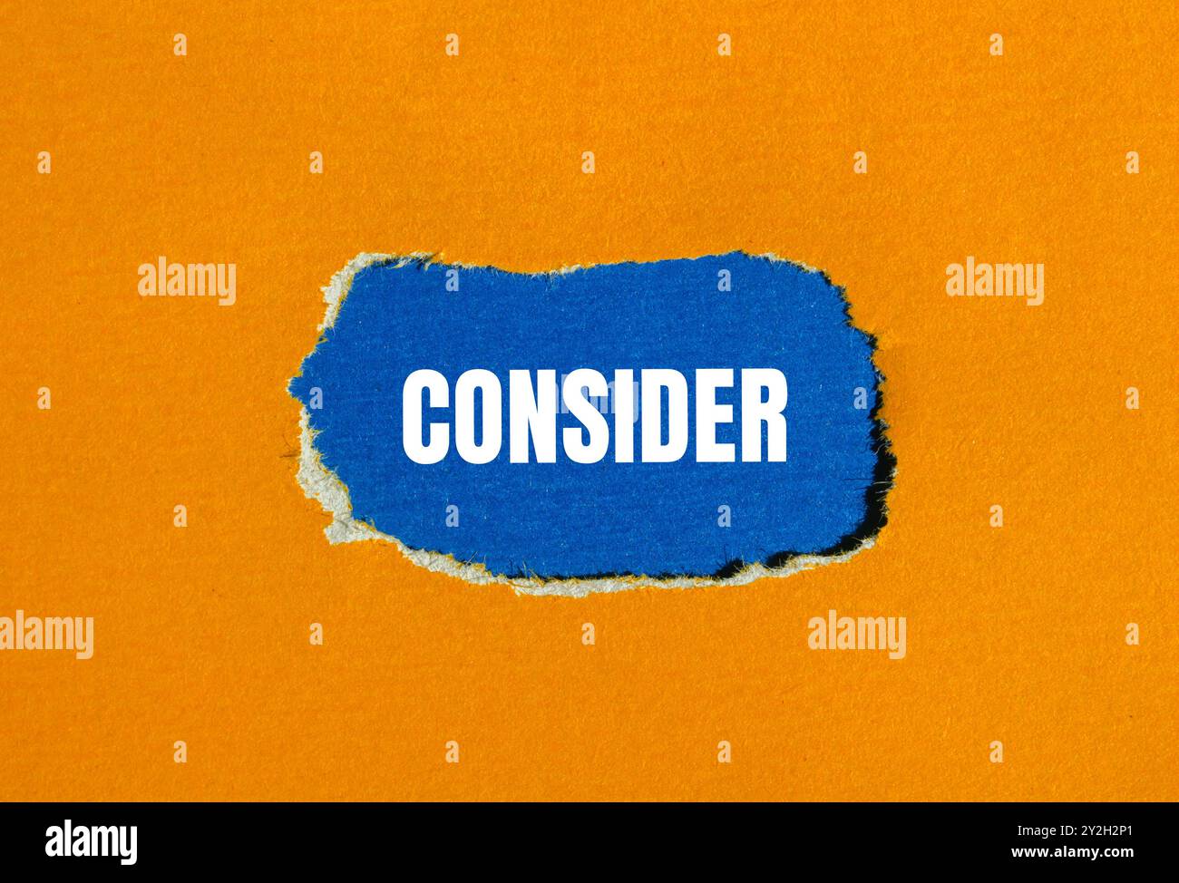 Consider message written on ripped torn orange paper with blue background. Conceptual consider symbol. Copy space. Stock Photo