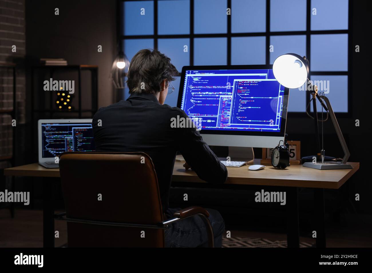 Young male programmer working with computers in office at night Stock Photo