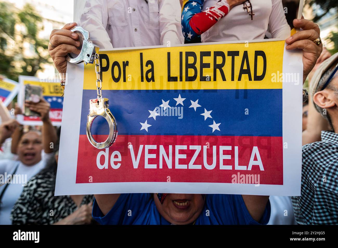 A woman carries handcuffs while holding a placards during a rally in front of the Spanish Parliament. Venezuelans living in Madrid gathered to protest against Nicolas Maduro and give support to opposition leader Maria Corina Machado and opposition presidential candidate Edmundo Gonzalez, coinciding with a debate inside the Parliament, initiative by the People's Party (PP) for recognizing Edmundo Gonzalez as the winner of the past elections and therefore the new president of Venezuela. Edmundo Gonzalez fled into exile in Spain on September 8 to find asylum, Stock Photo