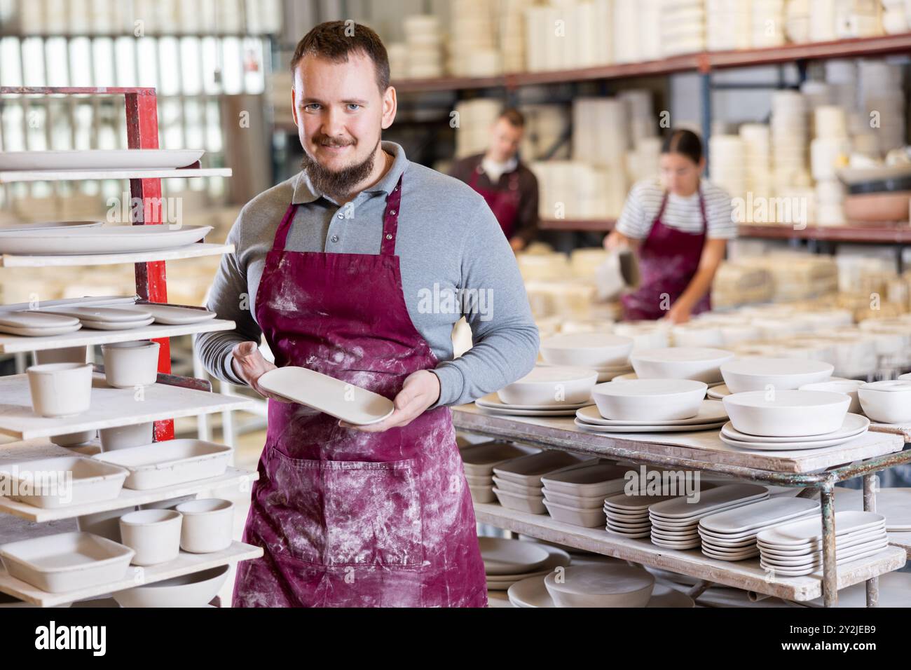 Enthusiastic ceramicist demonstrating handcrafted plates in ceramic studio Stock Photo