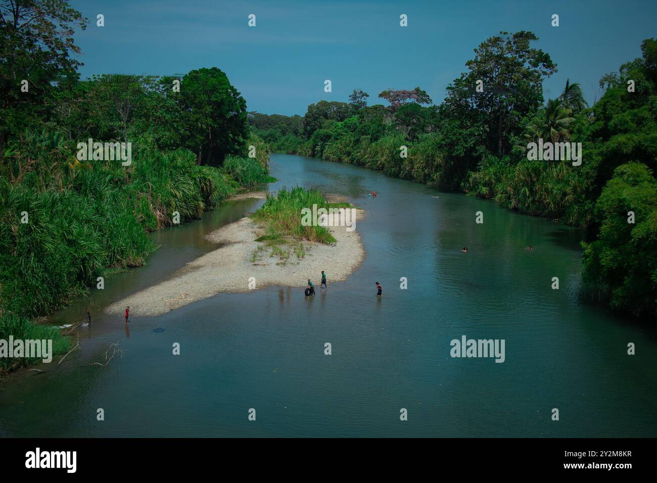 A group of younger locals is taking a bath in a river nearby. Typical ...