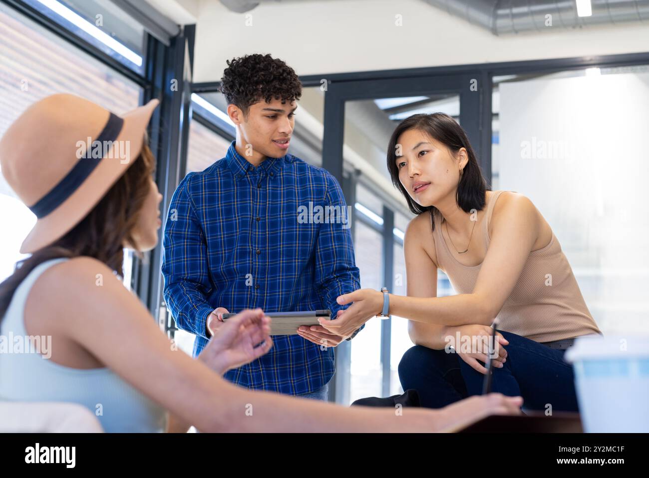 Discussing ideas on interior design project, diverse team collaborating using tablet in office Stock Photo