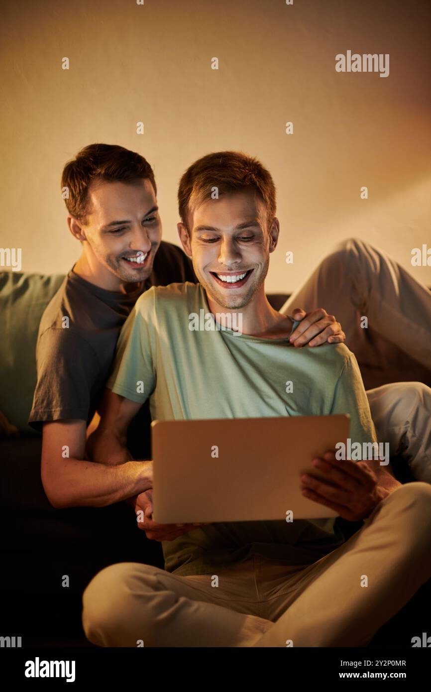 Two men share laughter and joy while watching something together. Stock Photo