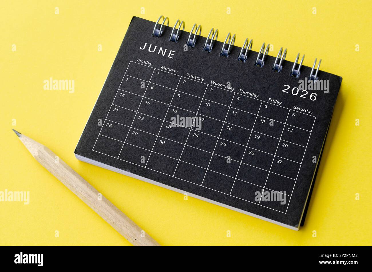 Top view of June 2026 calendar on black notepad with yellow background