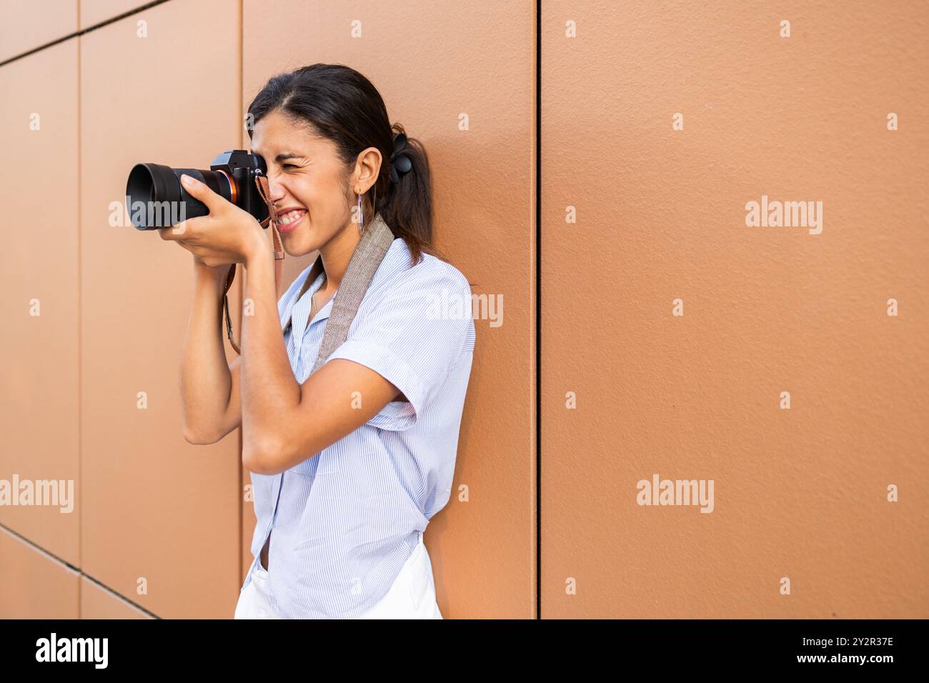 A joyful female student uses her DSLR camera to capture moments around ...