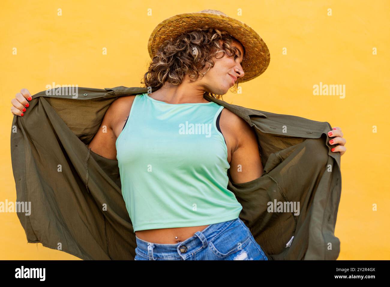 A woman with curly hair playfully poses and dances against a vivid ...