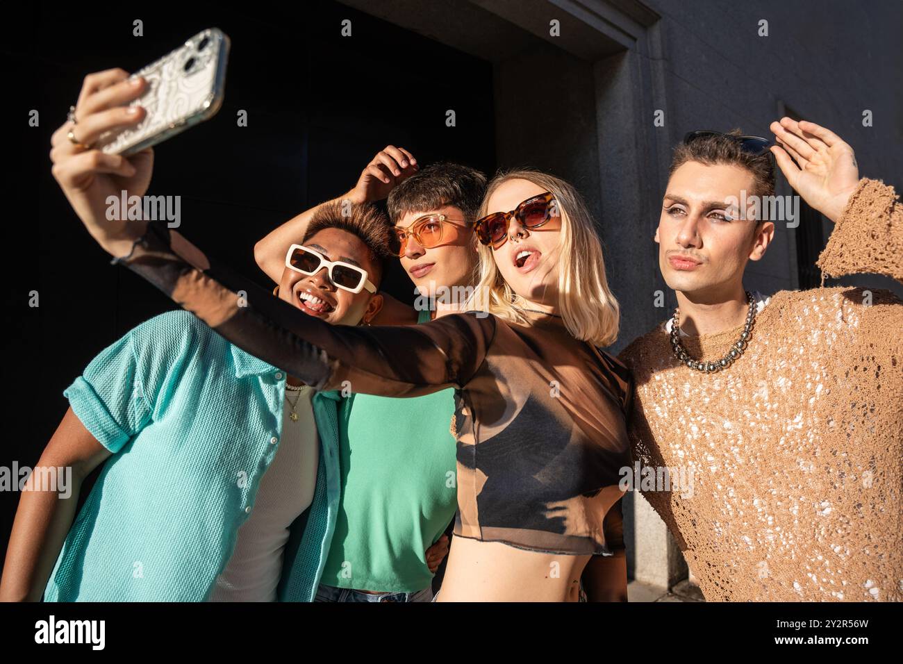 A diverse group of four LGBTQIA+ friends in stylish outfits, taking a ...