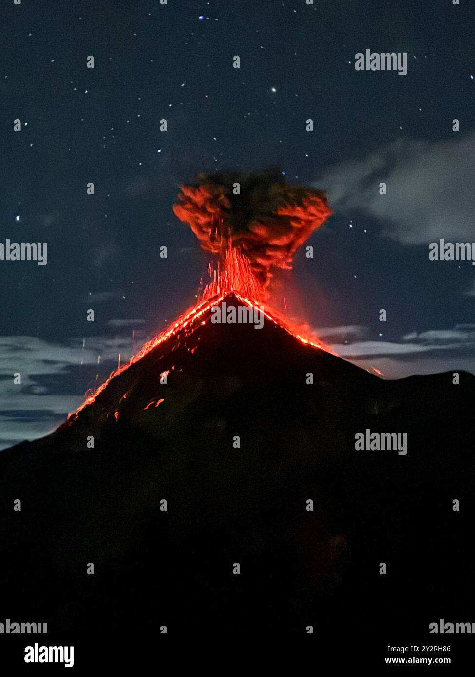 A dramatic nighttime capture of a volcanic eruption with glowing lava ...