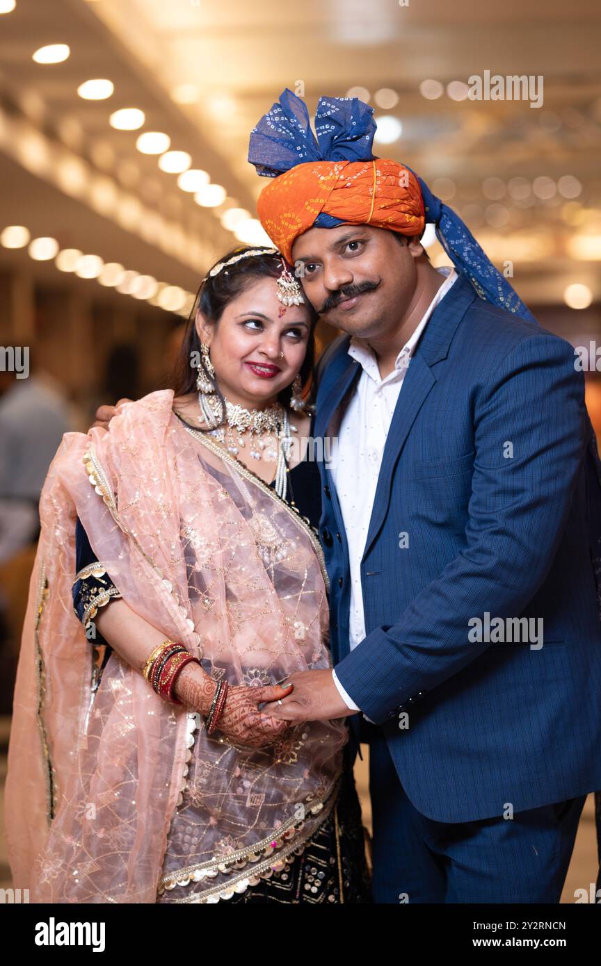 A couple in traditional Indian attire posing at a wedding event with a ...