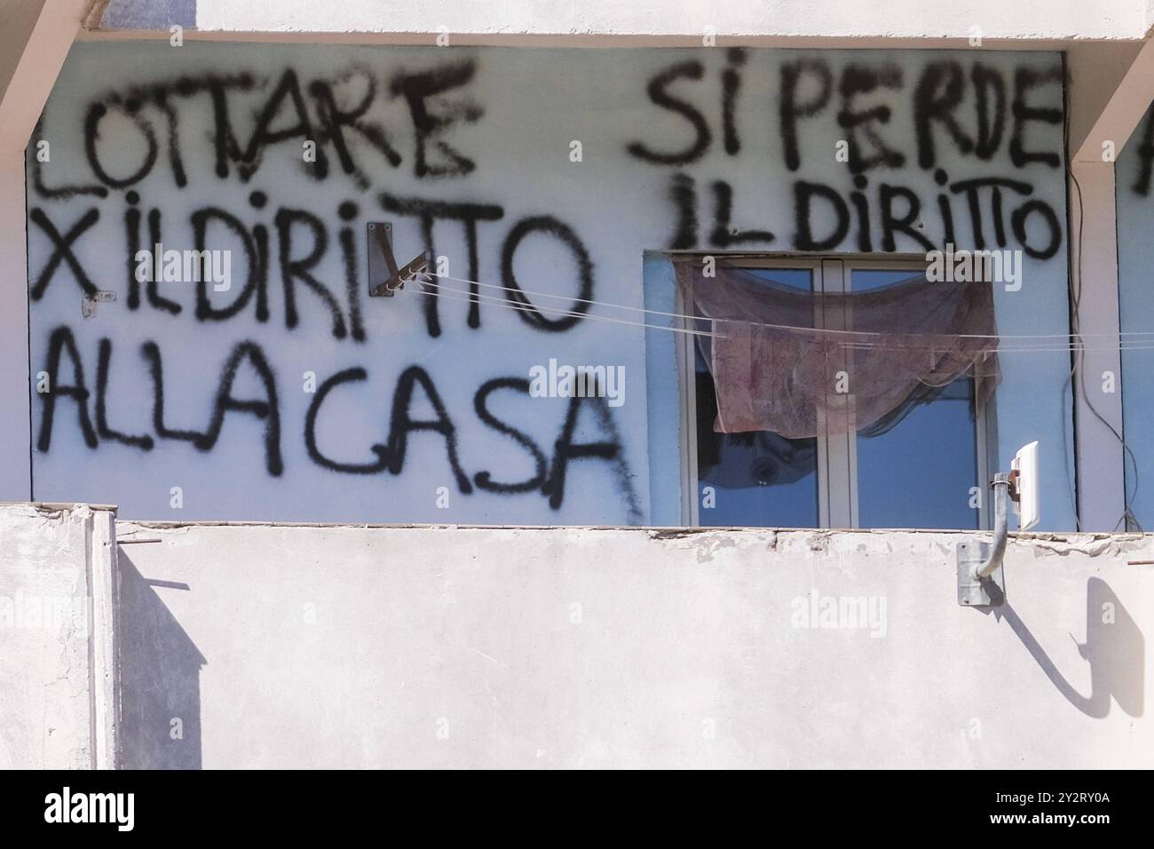 News - Vele of Scampia, Mayor Manfredi orders urgent eviction An inscription on the balcony of the sails reads Fight for the right to housing, you lose the right to life .The mayor of Naples Gaetano Manfredi has signed two ordinances for the ad horas eviction of the Vela Gialla and Vela Rossa in Scampia, the two buildings scheduled for demolition. The orders were signed for safety reasons and because of the risks threatening public and private safety . The two buildings are owned by the City of Naples and currently occupied, located in the Scampia district in Via della Resistenza, block C - Ve Stock Photo