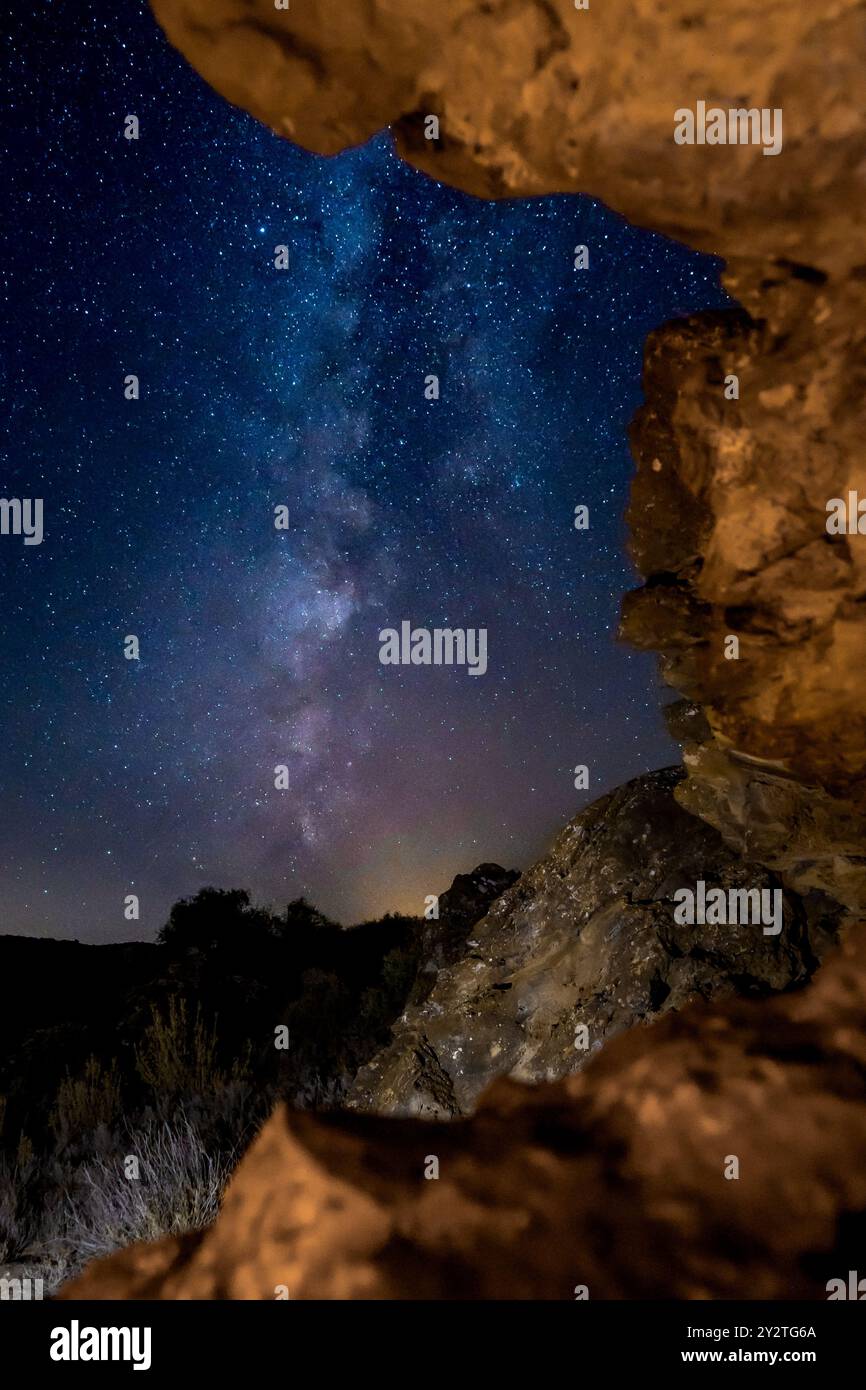 A stunning view of the Milky Way galaxy framed by rocky formations in a ...