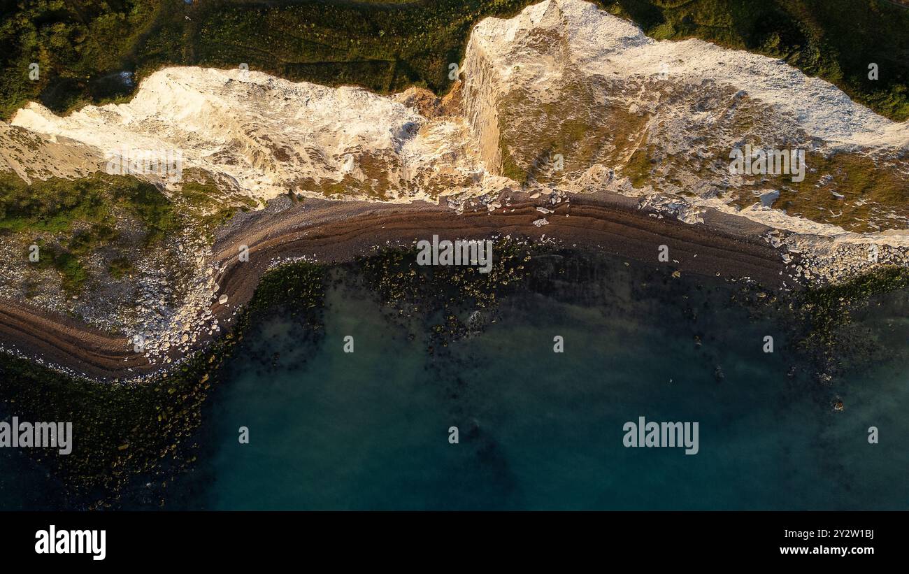 White Cliffs Water Rushing Aerial view of a rugged coastline with white cliffs, rocky beach, and ...