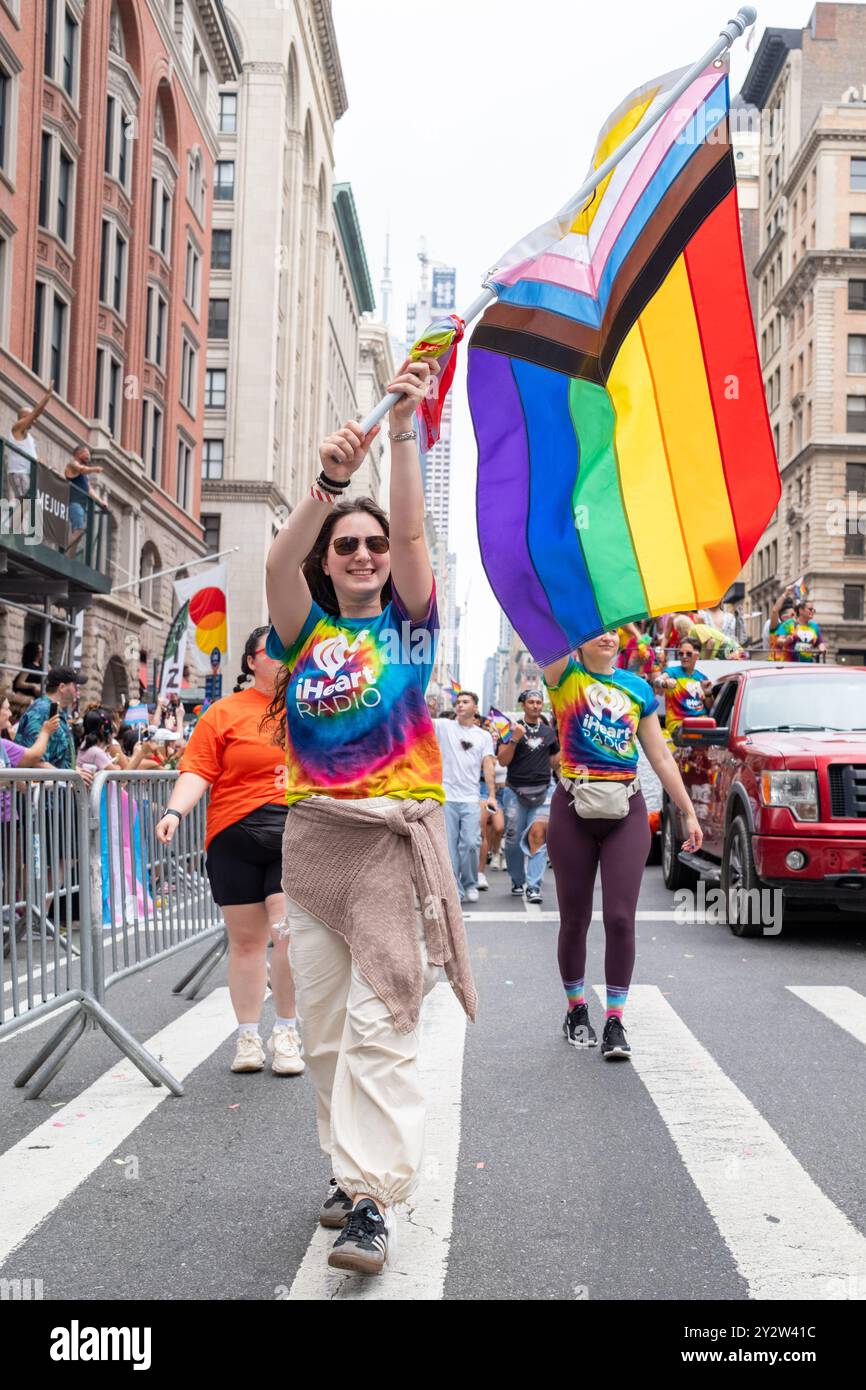 a woman holding a rainbow Pride flag in the street with other people ...