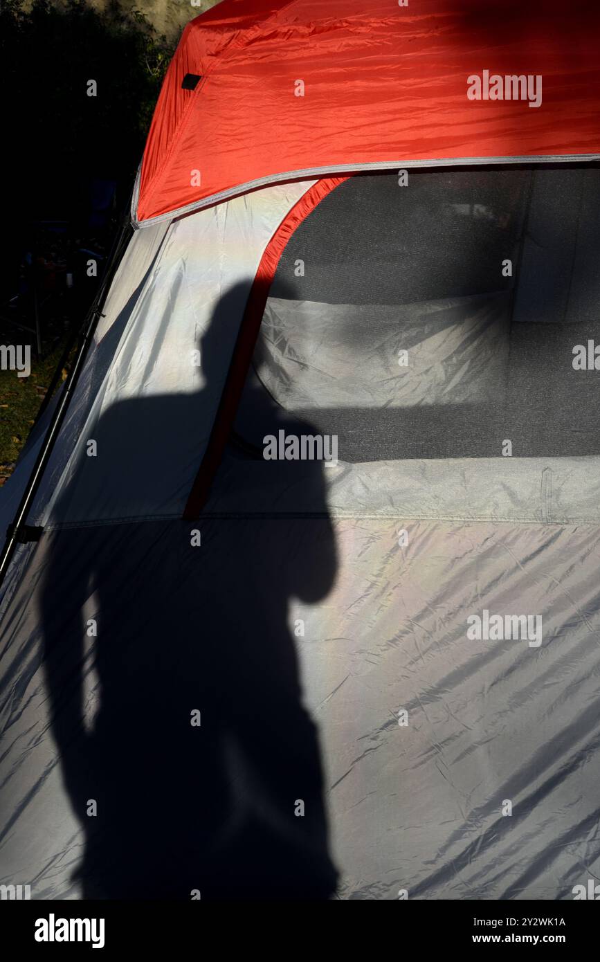 The shadow of a male photographer falls on the fabric of a red and grey ...